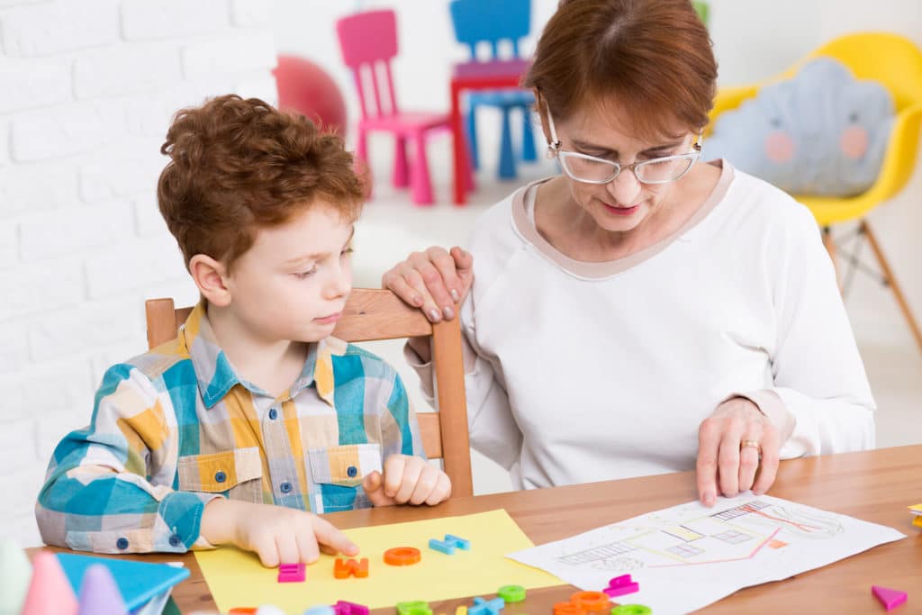 Teacher working with young boy on identifying pictures using plastic letters.