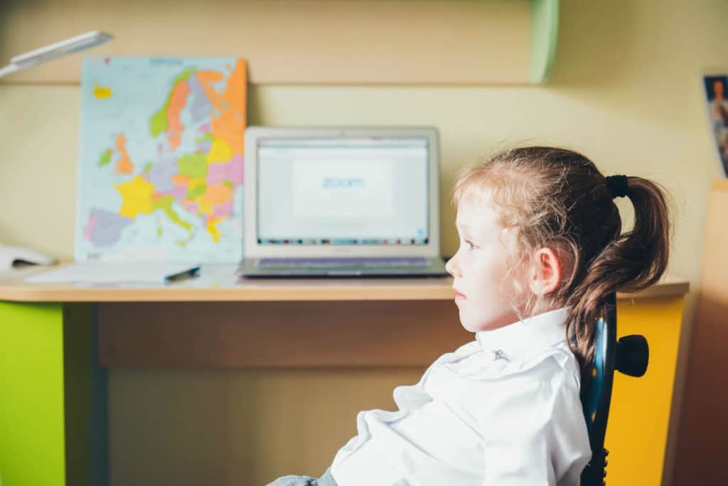 Young girl sitting in an office chair disinterested in her Zoom class.