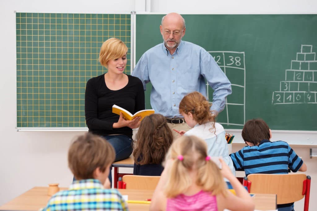 Two educators in front of a class of students.
