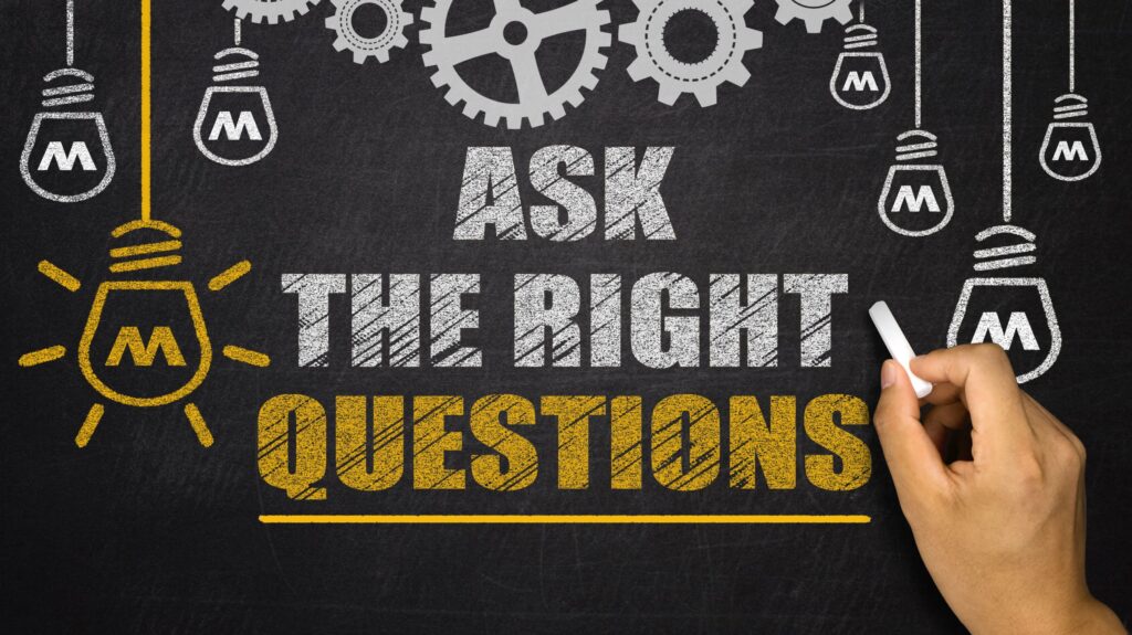 A portrait of someone writing on a chalkboard. It reads: “Ask the right questions.”