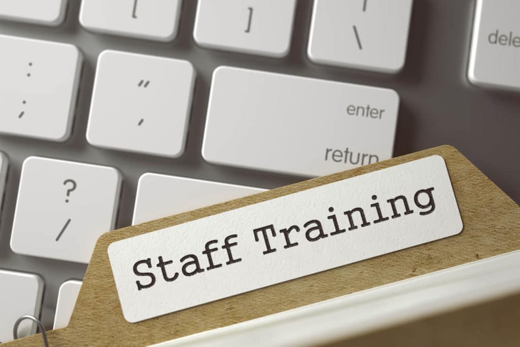 A folder labeled ‘staff training’ on top of a keyboard.