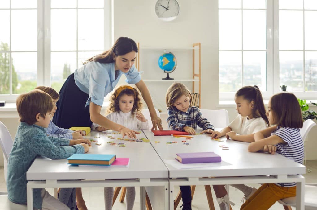 Group of young students sitting together at a table with their teacher.