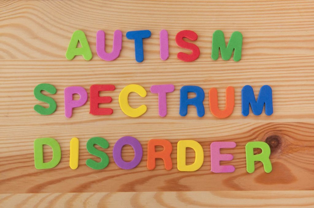 Colorful letters spell out Autism Spectrum Disorder on a wooden background.