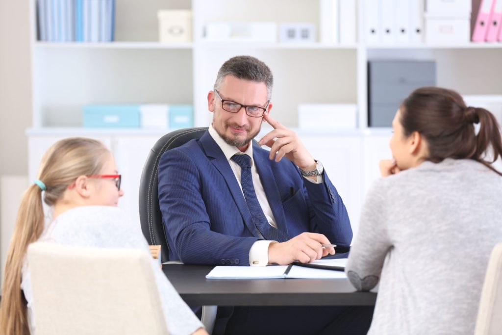 A student and her mother sit in a meeting with a school leader.
