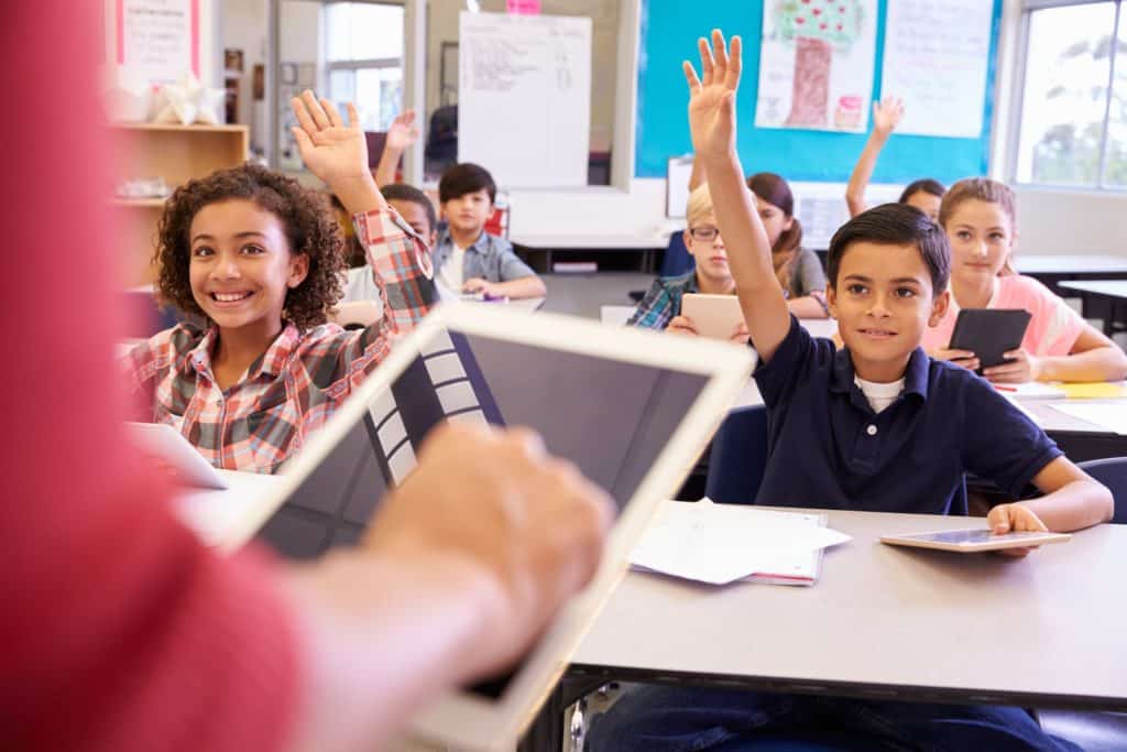 Teacher uses a tablet computer teaching an elementary school lesson.