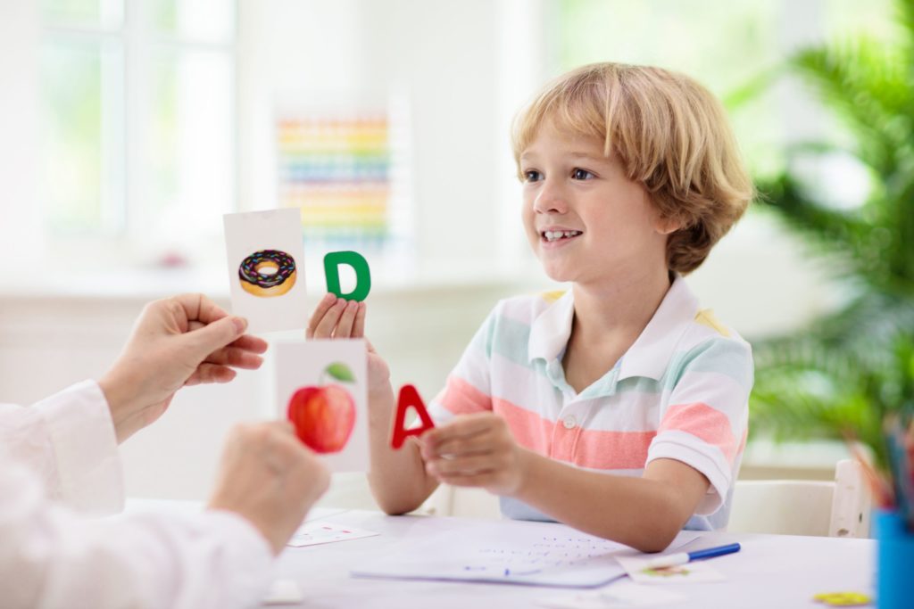 A young student practices flashcards with their teacher.