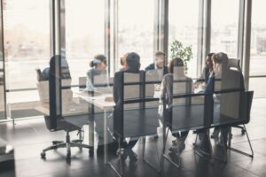 A group of professionals sit in a conference room, having a formal meeting.