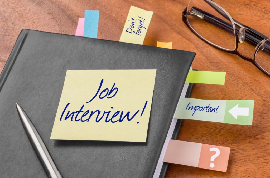 A close-up of a binder that has a Post-It note labeled, “job interview.”