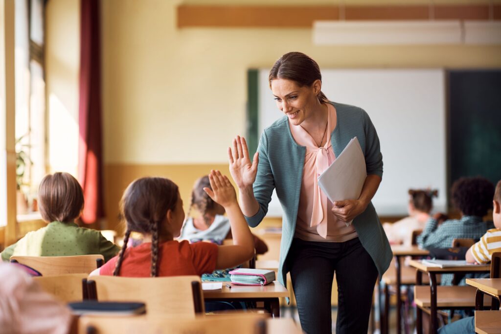 A teacher high-fives a little girl in her classroom, bonding with students.