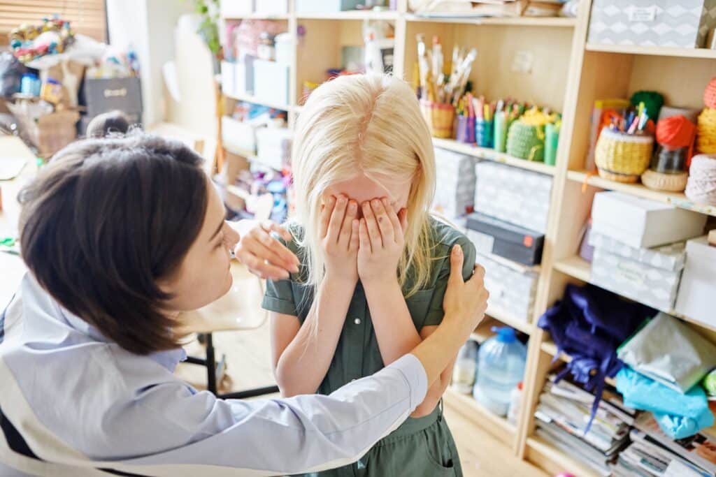 A teacher comforts a crying and upset student.