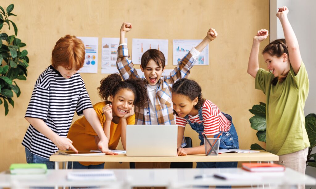 A group of students discusses and works together around a laptop.