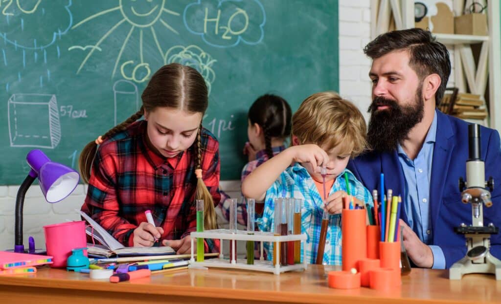 A teacher works with students, doing a science experiment with them as a part of an after-school program.
