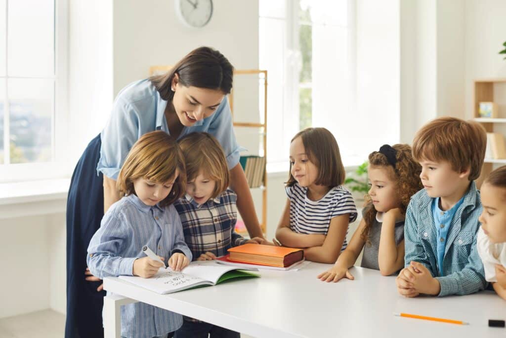 An early childhood educator helps her students work on their handwriting.