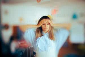 A teacher holds her head, appearing very anxious and stressed.