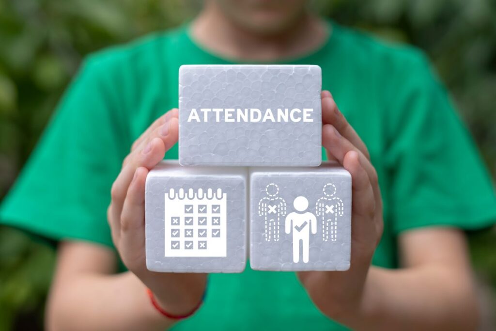 A close-up of a student holding blocks with icons on them that represent students being absent and school avoidance.