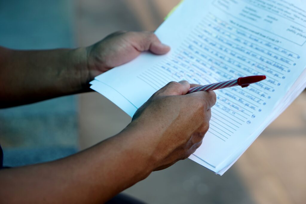 A close-up of a teachers hands as they grade a test.