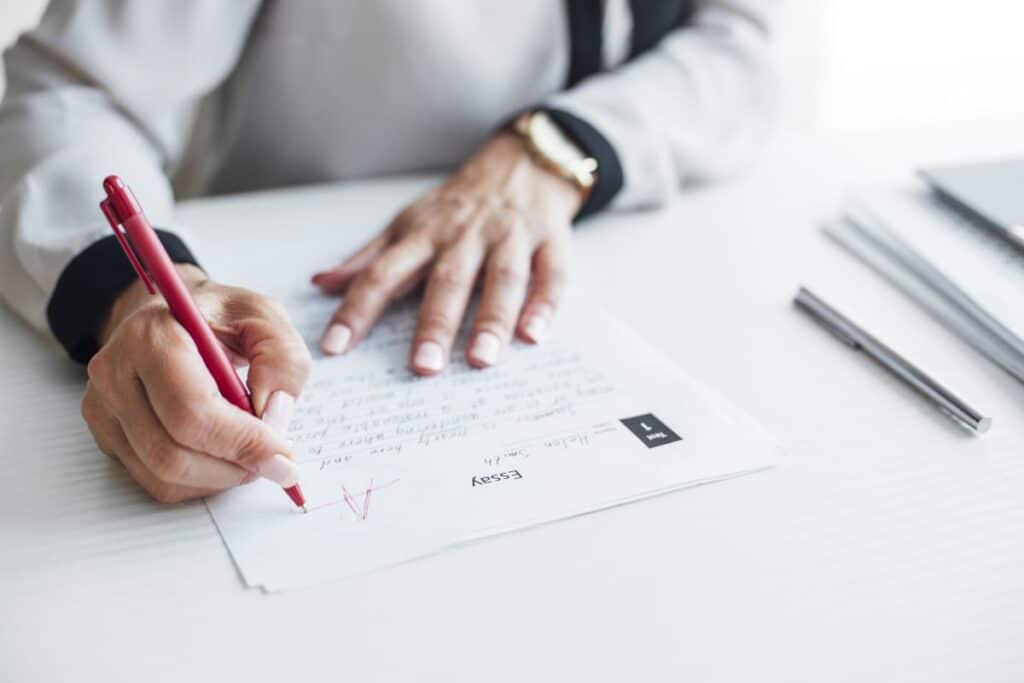 A close-up of a teacher’s hand grading an assessment.